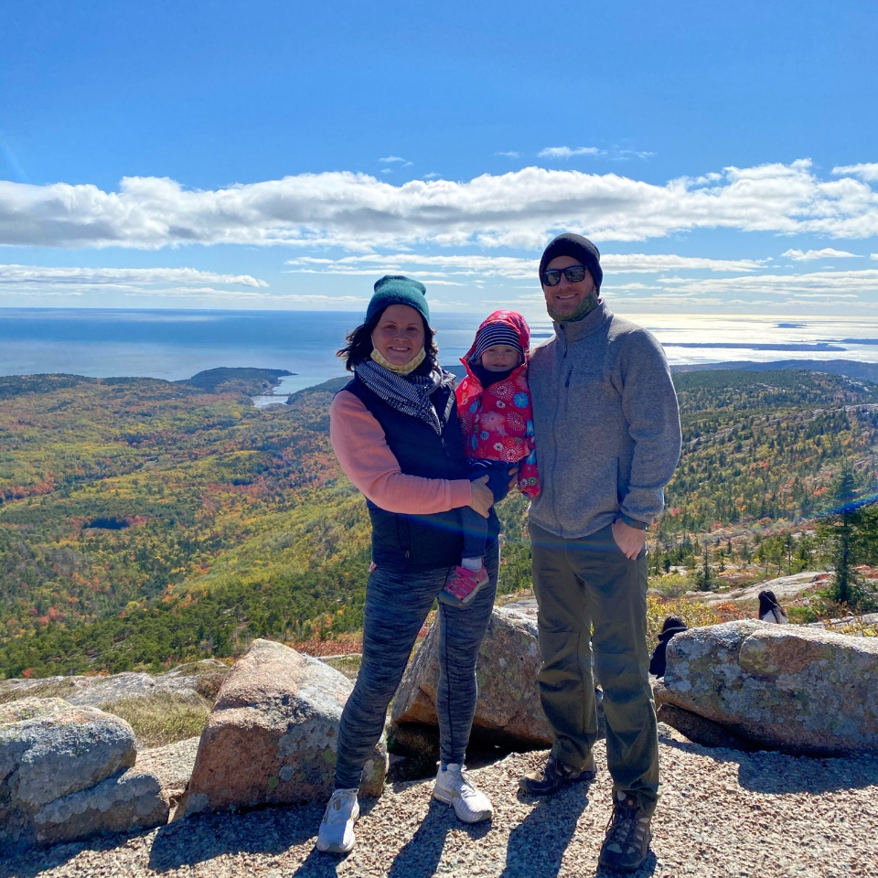 man, women and child smiling for picture on mountain top