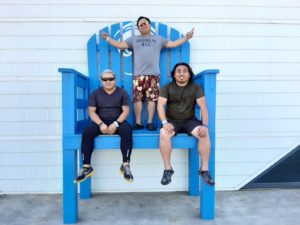 three men on an oversized blue chair