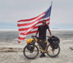 man standing next to bicycle and united states flag