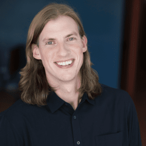 picture of a while male with long hair in a dark button up shirt