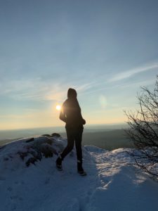 woman standing on snow covered grounds at sunset