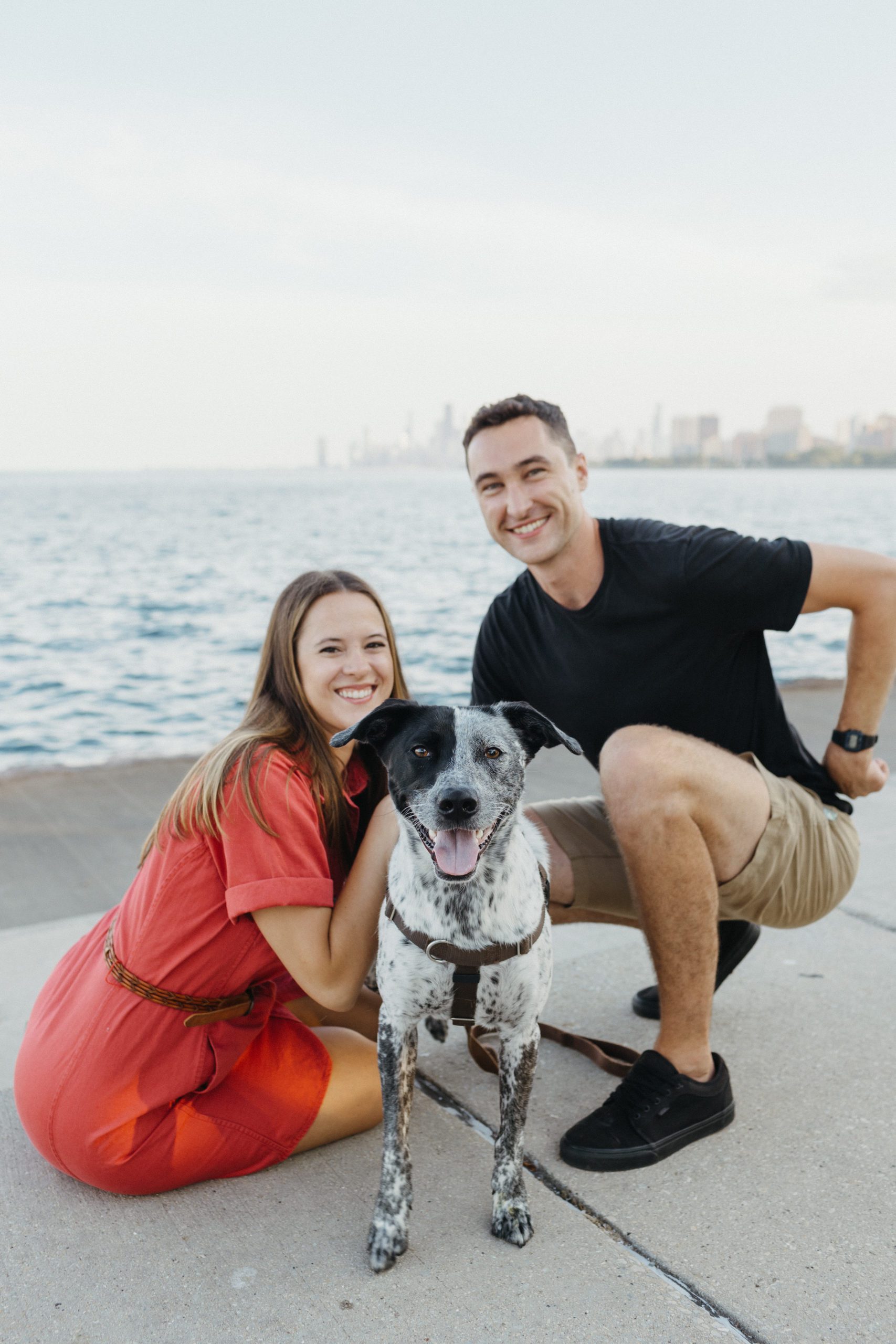 man, woman, and dog in front of lake michigan