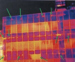 An infrared scan of a commercial office building with arrows point at locations of suspected heat loss